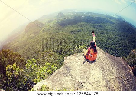 young woman hiker use smartphone taking photo on seaside mountain top