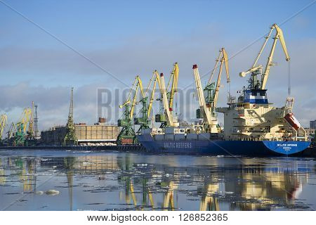 ST. PETERSBURG, RUSSIA - FEBRUARY 17, 2016: February sunny day at Kanonersky channel. Cargo cranes loading barges with cargo in big port of St. Petersburg