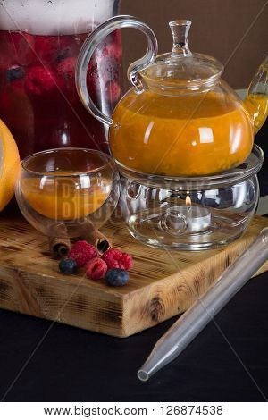 still life of tea and hookah on a wooden stand , forest and sea buckthorn berries .