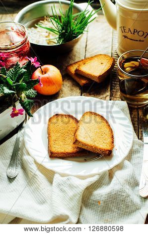 Toast with jam and cup of tea on old wooden table. Delicious toast with jam on table close-up. Fresh cherry jam with toast for breakfast on rustic wooden background. Sweet cherry jam on toast.