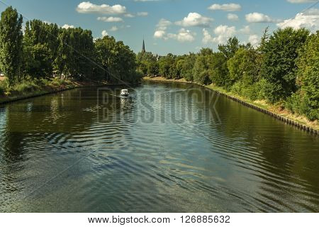 boattrip on an sunny day with a church spire in the backround and on both side of the river are green trees