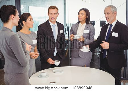 Businesspeople having tea and interacting during breaktime in office