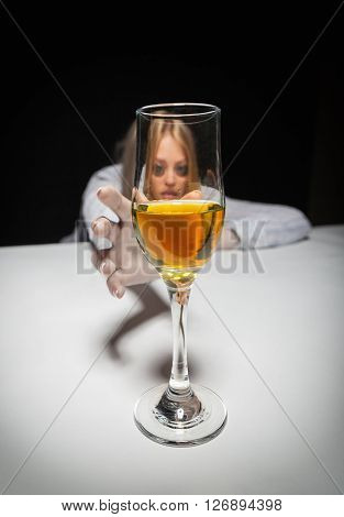 Young beautiful woman in depression drinking alcohol on dark background