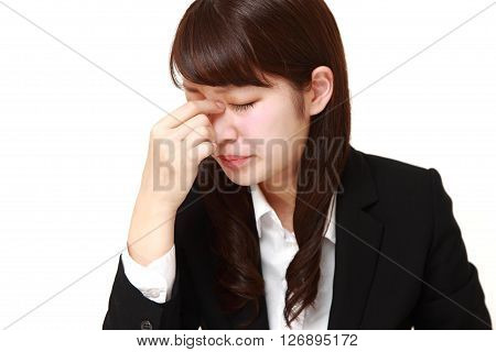 young Japanese businesswoman suffers from Asthenopia on white background
