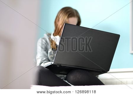Teen girl on a laptop in her bedroom
