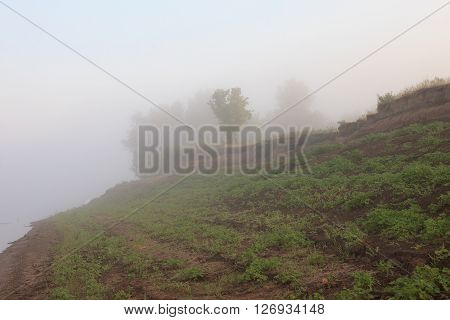 Mysterious Volga riverside in fog. Misty dawn early morning nature grassland landscape view in Russian countryside.