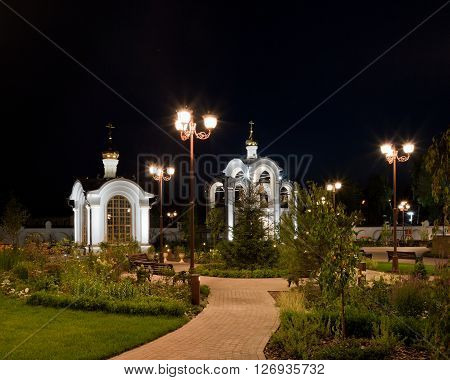 Orthodox temple complex. Architectural lighting. Internal territory of the complex. Street lamp in classic style chapel and bell tower. Sidewalks and landscaping