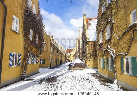 Augsburg Germany - January 17 2016:The Fuggerei and tourists. The Fuggerei is the world's oldest social housing complex still in use. It is a walled enclave within the city of Augsburg Bavaria.