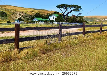 Rural ranch surrounded by grasslands and a rustic wooden fence