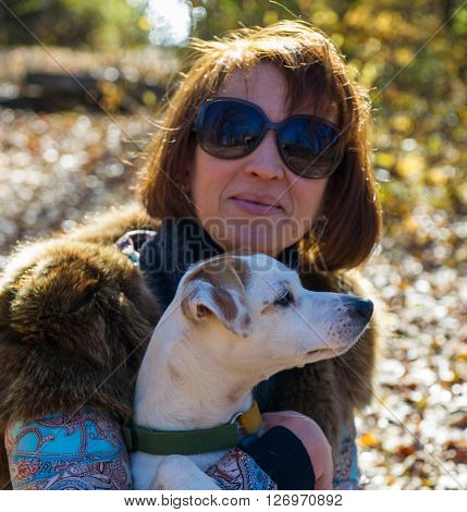 portrait of a woman with a dog on holiday in the autumn park  age of 40 years