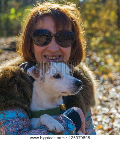 portrait of a woman with a dog on holiday in the autumn park,  age of 40 years