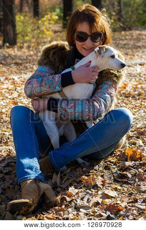 portrait of a woman with a dog on holiday in the autumn park  age of 40 years