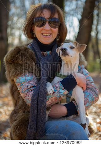 portrait of a woman with a dog on holiday in the autumn park  age of 40 years
