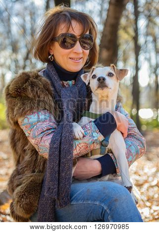 portrait of a woman with a dog on holiday in the autumn park  age of 40 years
