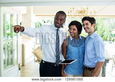 Real estate agent pointing while showing the house to couple