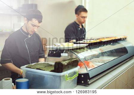 male cooks preparing sushi in the restaurant kitchen.