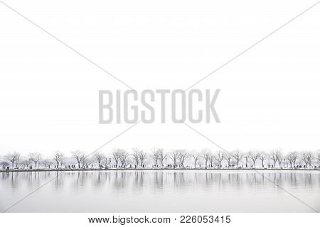 Landscape At Xihu Lake, Hangzhou, China, People Walking Across The Lake While Snowing In A Winter Da