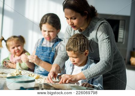 Mother Teaches Her Children How To Cook. Two Girls And The Boy Very Much Try. Their Faces In Flour, 