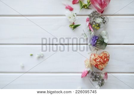 Petals And Cubes Of Ice Of Heart With Flowers Inside On A White Wooden Background