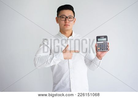 Confident Asian Man Showing Calculator And Pointing At Empty Screen. Young Book Keeper Presenting Pr
