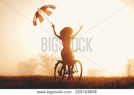 A Young Girl With Umbrella Riding On A Bike