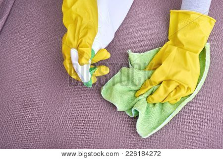 A Picture Of Hands In Yellow Gloves Cleaning The Sofa.