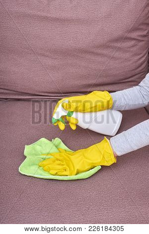 A Picture Of Hands In Yellow Gloves Cleaning The Sofa.