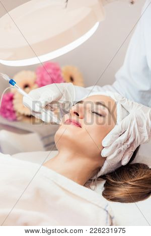 Beautiful woman relaxing during non-invasive facial treatment for rejuvenation in a contemporary beauty center with innovative equipment