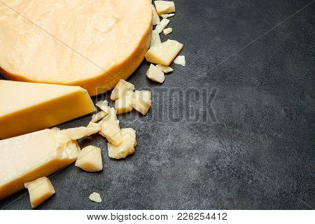 Head Of Parmesan Or Parmigiano Hard Cheese And Pieces On Concrete Background Or Table