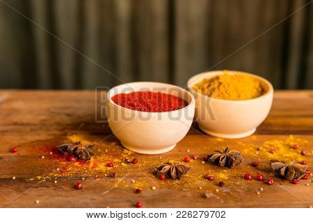 Close Up Two Bowls Filled With Red Paprika And Yellow Turmeric Powder On Dark Wooden Table Covered W