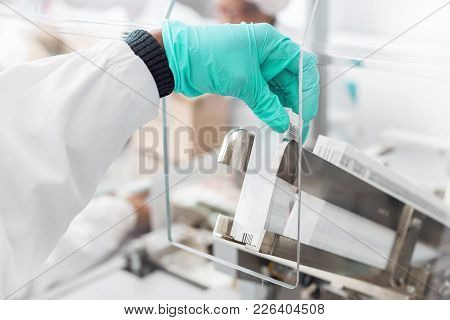 Hand Placing Labels Into A Label Inserting Machine. The Machine Puts Labels Inside Medicine Packagin