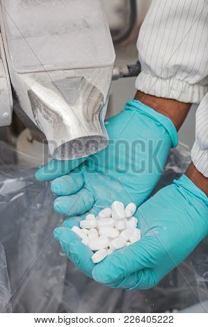 Medical Pills Being Inspected By Hand From Machine That Is Sorting Them. Pharmaceutical Manufacturin