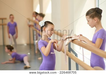 Young Beautiful Ballerinas Close Up. Two Lovely Girl With Ballet Shoes In Ballet Dance Studio. Frien