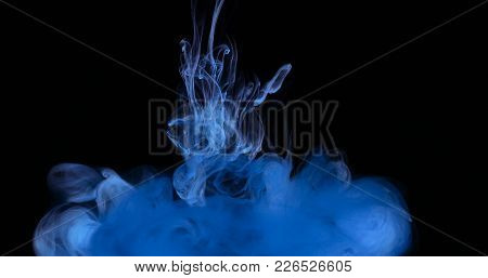 Blue Drops, Waves And Clouds Of Ink Creating Dynamic Shapes In Water. Abstract Effects Of Paint Colo