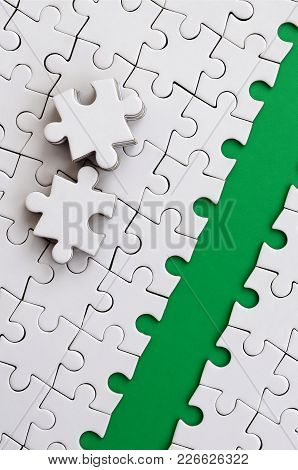 The Green Path Is Laid On The Platform Of A White Folded Jigsaw Puzzle. The Missing Elements Of The 