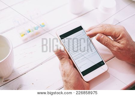 Hands Of Senior Patient Filling Out Information Form Online On His Smartphone