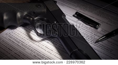 Black Handgun And Background Check Paperwork With Dishonorable Discharge Clause Obvious