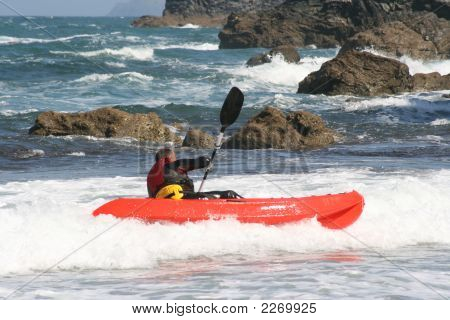 Mann im Meer in der Nähe von Felsen Kajak