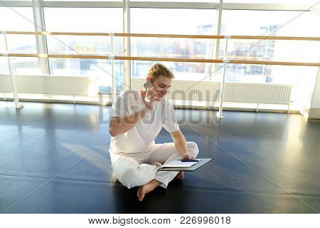 Fitness Trainer Discussing Details With New Client On Smartphone In Gym, Handsome Guy Sitting On Par