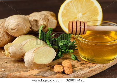 Honey With Ginger, Lemon And Mint And Nuts On Wooden Board And Grey Background.