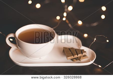 Cup Of Green Tea With Matcha Chocolate And Floers On Tray Over Lights. Good Morning. Breakfast.