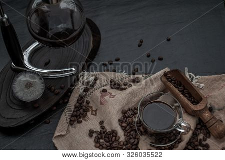 Coffee Style, Cup Of Coffee And Coffee Beans Roating With Old Wooden Scoop And Coffee Beans Around O