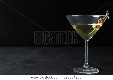 Glass Of Classic Dry Martini With Olives On Dark Table Against Black Background. Space For Text