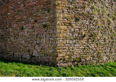 Corner Of An Old Medieval Fortress Wall. The Wall Is Made Of Sandstone Blocks. One Side Of The Wall 
