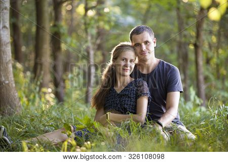 Youg Couple, Man And A Woman Sitting Together Outdoors Enjoying Nature.