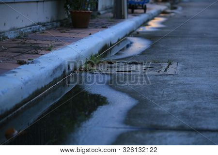 Water Puddle On The Street. Poor Drainage System Left Water Near Catch Basin Drain Inlet On A Concre