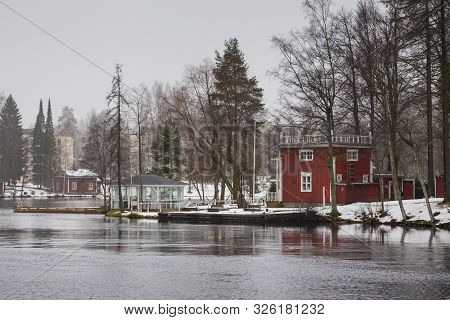 Small, Red, Wooden House On The Bank Ruotsalainen Lake. Winter Landscape, Heinola, Finland.