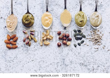 Nuts And Seeds Butter On A Spoons With Ingredients. Homemade Raw Organic Almond, Hazlenut, Cashew, P
