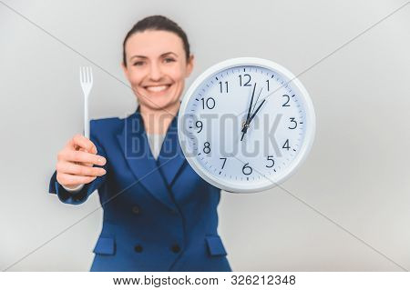 Blurred Lovely Teacher Is Ready For Dinner Break, Extending Fork And White Clock To The Camera.