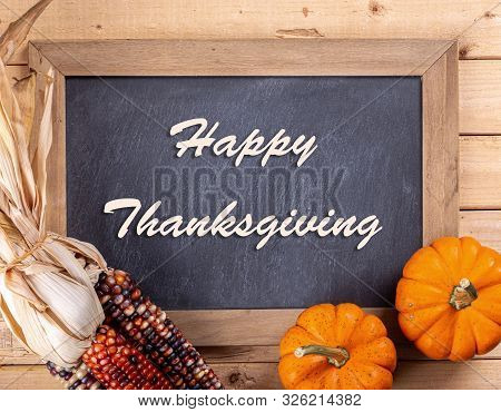 Happy Thanksgiving Text Written On A Chalkboard With Colorful Mini Pumpkins And Indian Corn